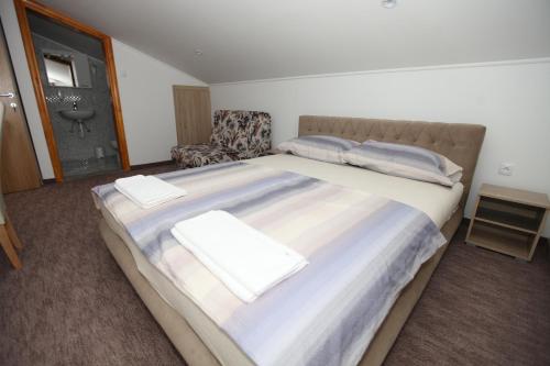 a bedroom with a large bed with pillows and a chair at Ninkovic in Trebinje