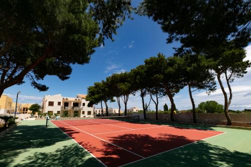 a tennis court with trees in the foreground at Boa Vista San Vito - Area Fitness, Barbecue Area, Tennis Court in San Vito lo Capo