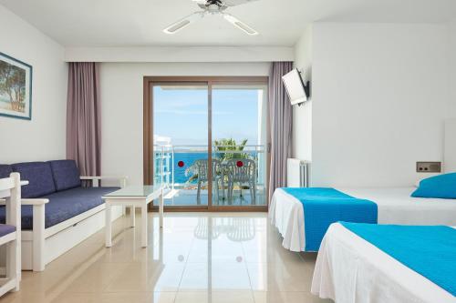 a hotel room with two beds and a view of the ocean at Aparthotel Nereida in San Antonio Bay