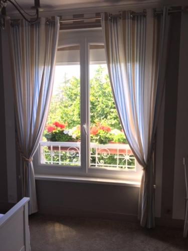 a window with curtains and flowers in a room at La Nouvelle Criqueboise in Criquebeuf-en-Caux