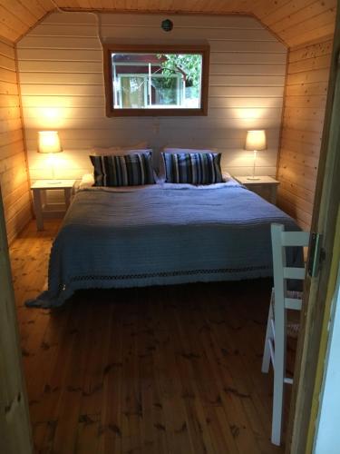 a bedroom with a bed with two lamps and a window at Ollila Rantamökit in Kerimäki