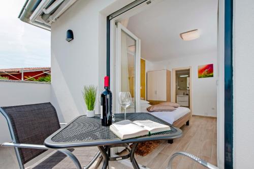 a room with a table with a wine bottle and books at Apartment and Studio Tereza in Rovinj