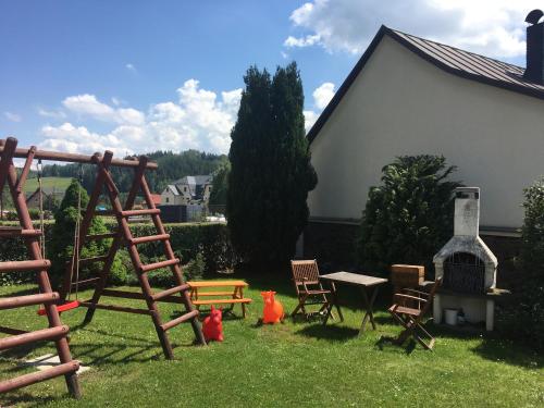a yard with a playground with chairs and a fireplace at Penzion Na Solné stezce in Kašperské Hory