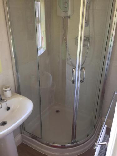 a shower with a glass door next to a sink at Eden Cottage in Haltwhistle