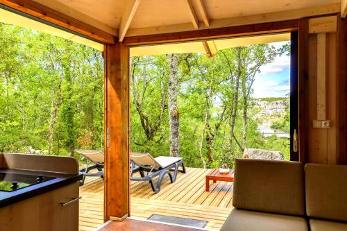 a screened in porch with a kitchen and a patio at Cabanes Lodges Le Servière in Balazuc