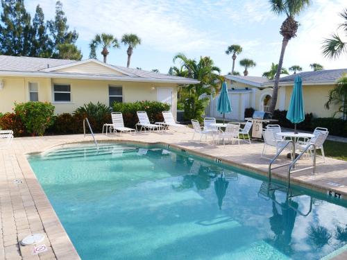 a swimming pool with chairs and umbrellas next to a house at The Sea Spray Resort in Siesta Key