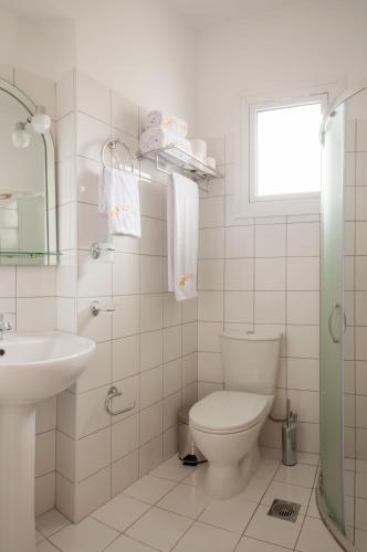 a white bathroom with a toilet and a sink at Studios Angeliki in Lassi
