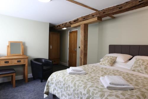 a bedroom with a bed with a desk and a chair at The Kings Head in New Buckenham
