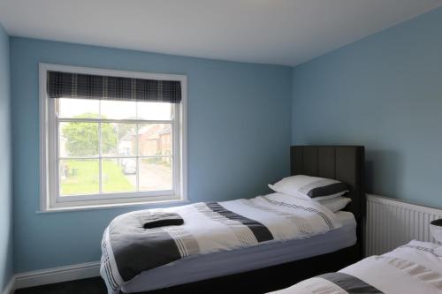 a blue room with two beds and a window at The Kings Head in New Buckenham