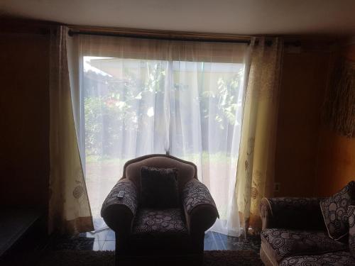 a chair sitting in front of a window with curtains at Cabaña Tongariki in Hanga Roa