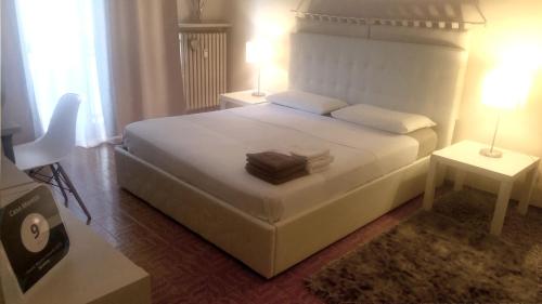 卡薩萊蒙費拉托的住宿－Casa Moretti，卧室配有一张白色床、两张桌子和两盏灯。
