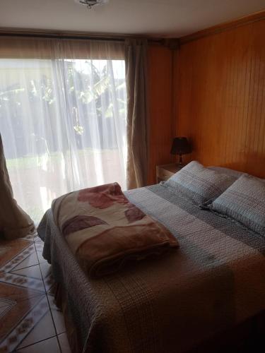 a bedroom with a bed and a large window at Cabaña Tongariki in Hanga Roa
