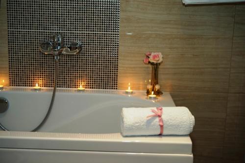 a bathroom with a bath tub with candles and a rose at Hotel Royal Gold City - Hotel Ruža in Sarajevo