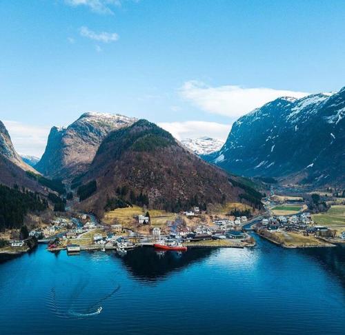 una piccola cittadina in mezzo a un fiume con montagne di Sogn Hotel a Vadheim