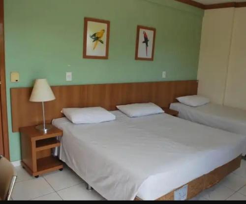 2 camas individuales en un dormitorio con una lámpara en una mesa en Caldas Novas Golden Dolphin, en Caldas Novas