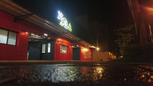 a red building with a neon sign at night at Travel Port Motel in Kaohsiung