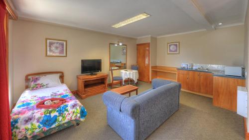a bedroom with a bed and a couch and a television at Hatchers Richmond Manor in Richmond