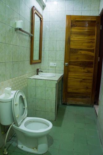 a bathroom with a toilet and a sink and a door at Putu Guest House in Canggu