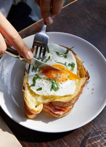 Uma pessoa cortando um sanduíche de café da manhã com um garfo. em Kirketon Hotel Sydney em Sidney