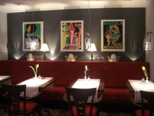 a restaurant with tables and chairs and posters on the wall at Hotel Brunnenhof in Hanau am Main