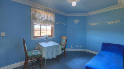 a blue bedroom with a table and chairs and a bed at Hatchers Richmond Manor in Richmond
