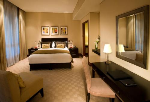 a hotel room with a bed and a desk at Shangri-La Hotel Apartments Qaryat Al Beri in Abu Dhabi
