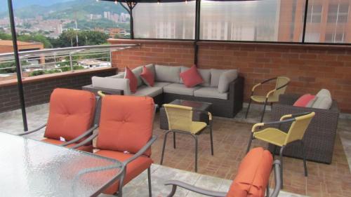 patio con sofá y sillas en el balcón en The 9's Apartahotel, en Medellín