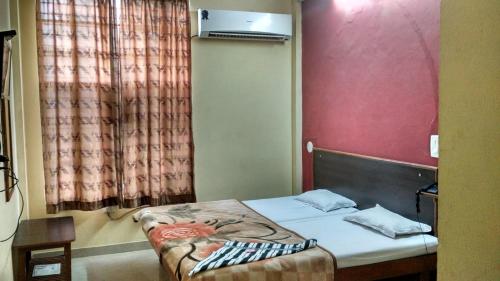 a small bed in a room with a red wall at Hotel Shiromani Palace Udaipur in Udaipur