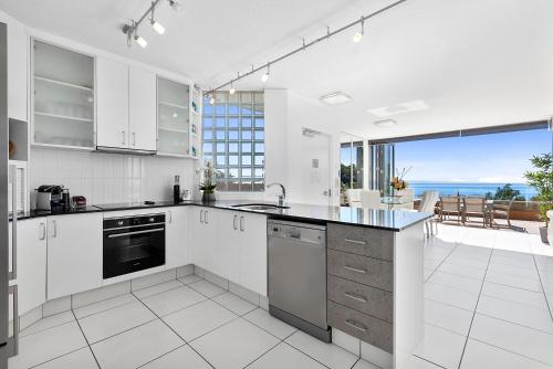 a kitchen with a white counter top and white cabinets at Picture Point Terraces in Noosa Heads