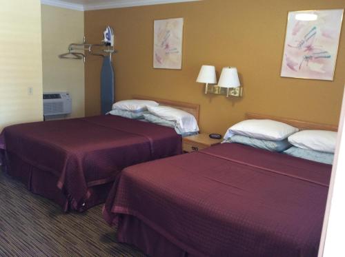 Habitación de hotel con 2 camas con sábanas rojas en Timberline Motel, en Lone Pine
