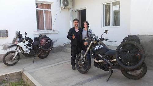 ホジェンドにあるHostel Sharq 21の二輪車の横に立つ男女