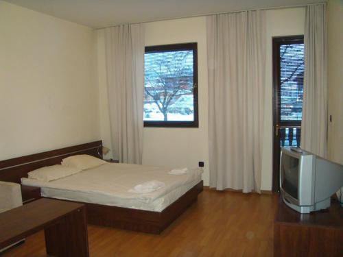 a small bedroom with a bed and a television at Fortuna Apartments in Bansko
