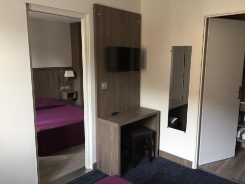 a room with a bed and a desk and a mirror at Hôtel Mont-Brison in Briançon