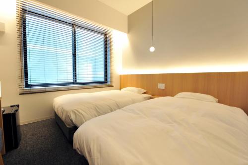 a hotel room with two beds and a window at FUGASTAY Shijo Omiya in Kyoto