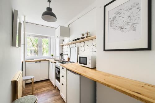 a kitchen with white cabinets and a wooden counter top at Chmielna Hammock Apartment in Warsaw