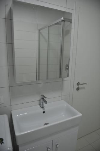 Un baño blanco con lavabo y espejo. en Cassiopeia Apartament, en Tirana