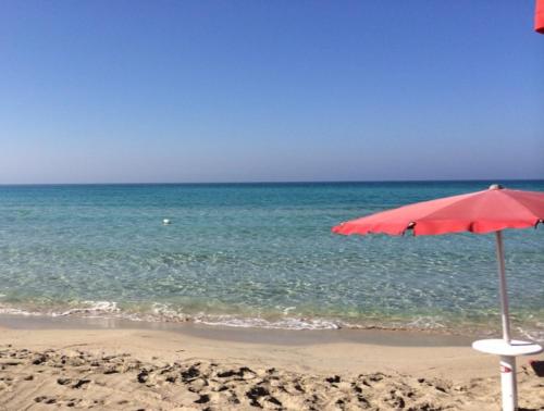 a beach with a red umbrella and the ocean at Borgoincorte in Martano