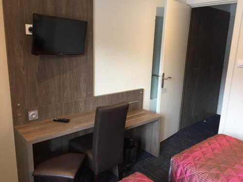a room with a desk with a television and a bed at Hôtel Mont-Brison in Briançon