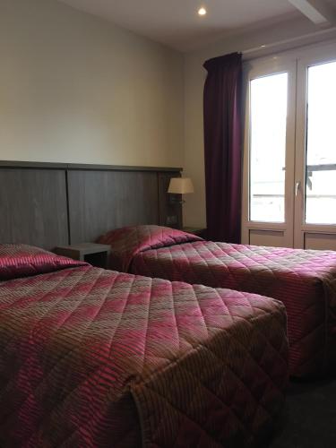 a hotel room with two beds and a window at Hôtel Mont-Brison in Briançon