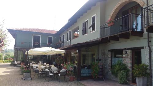 a building with tables and chairs and an umbrella at Trattoria Del Bivio in Cerretto Langhe