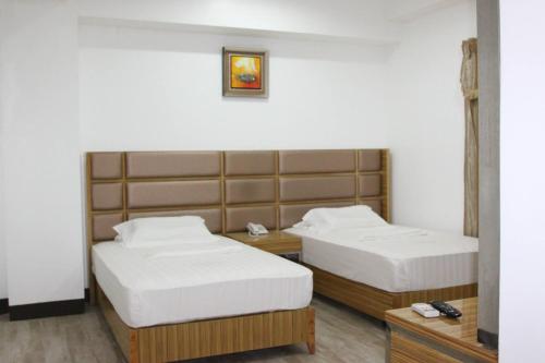 a hotel room with two beds with white sheets at Jeamco Royal Hotel-Palawan in Puerto Princesa City