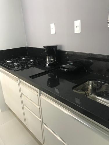 eine Küche mit einer schwarzen Arbeitsplatte und einem Waschbecken in der Unterkunft Apart Príncipe Barra in Salvador