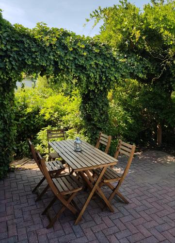 a wooden table and two chairs sitting next to a hedge at Hanse Hotel Buxtehude in Buxtehude