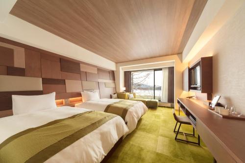 Tateshina的住宿－Izumigo AMBIENT Tateshina Hotel，酒店客房配有两张床和一张书桌