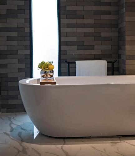 a white bath tub in a room with a table at Paco Hotel Chebeinan Metro Guanghzou-Free Shuttle Bus For Canton Fair in Guangzhou