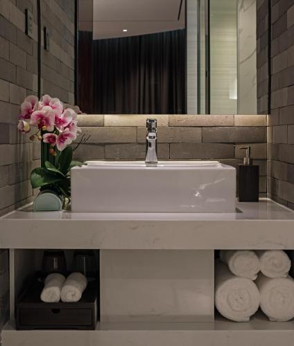 a bathroom sink with a vase of flowers and towels at Paco Hotel Chebeinan Metro Guanghzou-Free Shuttle Bus For Canton Fair in Guangzhou