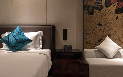 a hotel room with two beds and a chair with a pillow at Paco Hotel Chebeinan Metro Guanghzou-Free Shuttle Bus For Canton Fair in Guangzhou