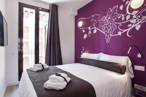 1 dormitorio con pared morada y toallas en la cama en Habitat Apartments ADN, en Barcelona