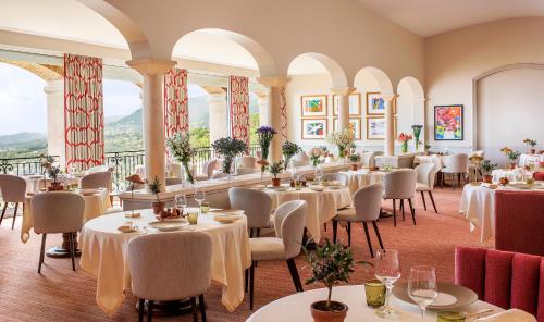 a restaurant with white tables and chairs and windows at Château Saint-Martin & Spa, Oetker Hotels in Vence