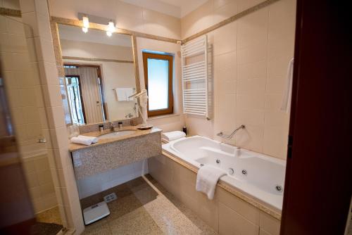 La salle de bains est pourvue d'une baignoire, d'un lavabo et d'un miroir. dans l'établissement Club de Vacanta Mediterraneo, à Legian
